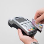 Commerciante utilizza un POS per elaborare un pagamento con carta di credito.